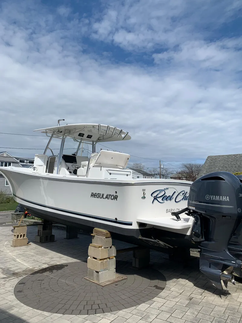 Slide: The Image of 2019 Regulator 31 FS boat on blocks, featuring Yamaha engines, under a partly cloudy sky. - 3