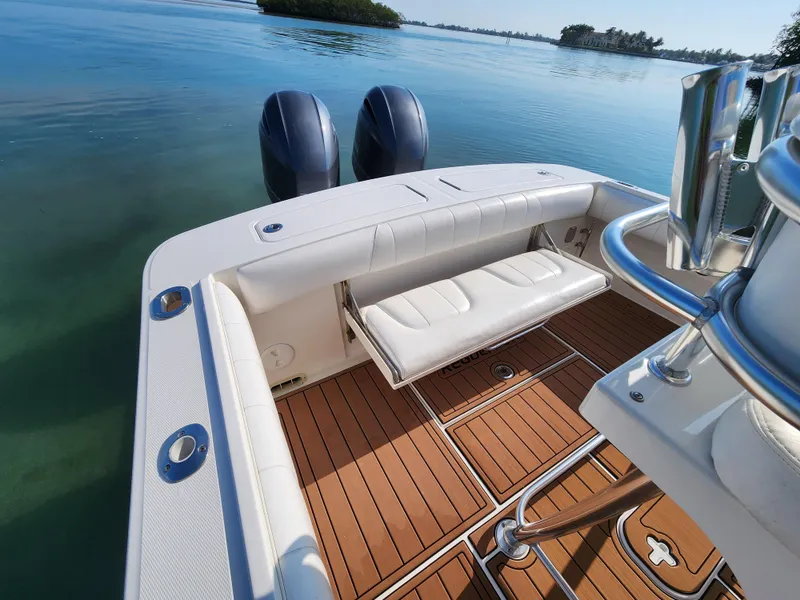 Slide: The Image of 2015 Regulator 25 boat with dual engines, teak deck, and cushioned seating on calm water. - 14