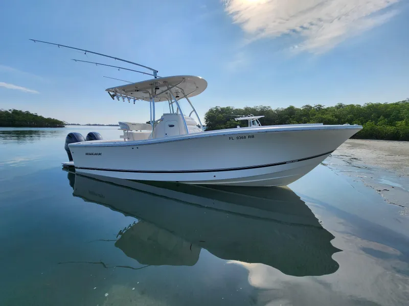 Slide: The Image of 2015 Regulator 25 boat on calm water, clear sky, and lush greenery. - 2