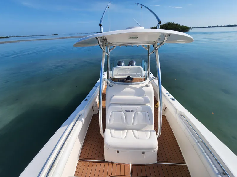 Slide: The Image of 2015 Regulator 25 boat on calm water, featuring sleek design and spacious deck. - 21