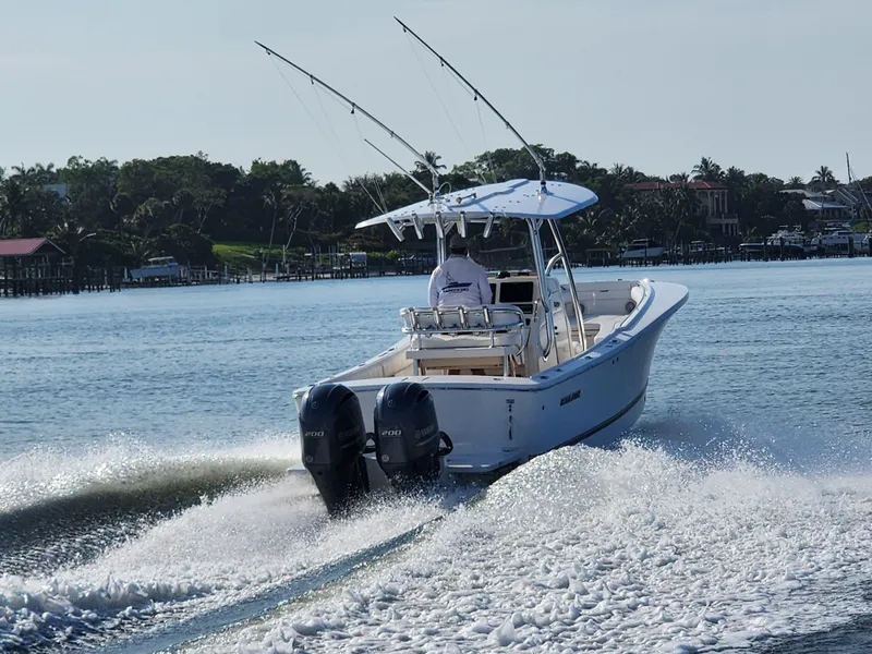 Slide: The Image of 2015 Regulator 25 boat cruising on a calm lake with dual engines. - 24