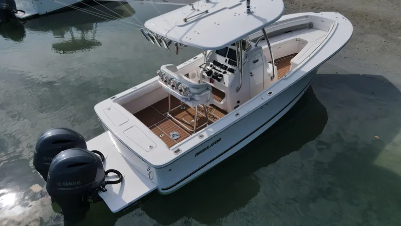 Slide: The Image of 2015 Regulator 25 boat with dual Yamaha engines, docked in calm water. - 3