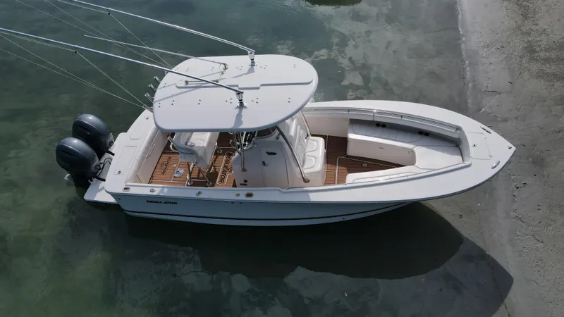 Slide: The Image of 2015 Regulator 25 boat with dual engines, docked on a sandy shore. - 4