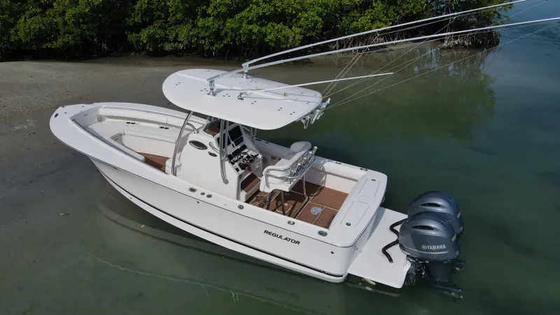 Slide: The Image of 2015 Regulator 25 boat with dual engines, docked near a sandy shore. - 6