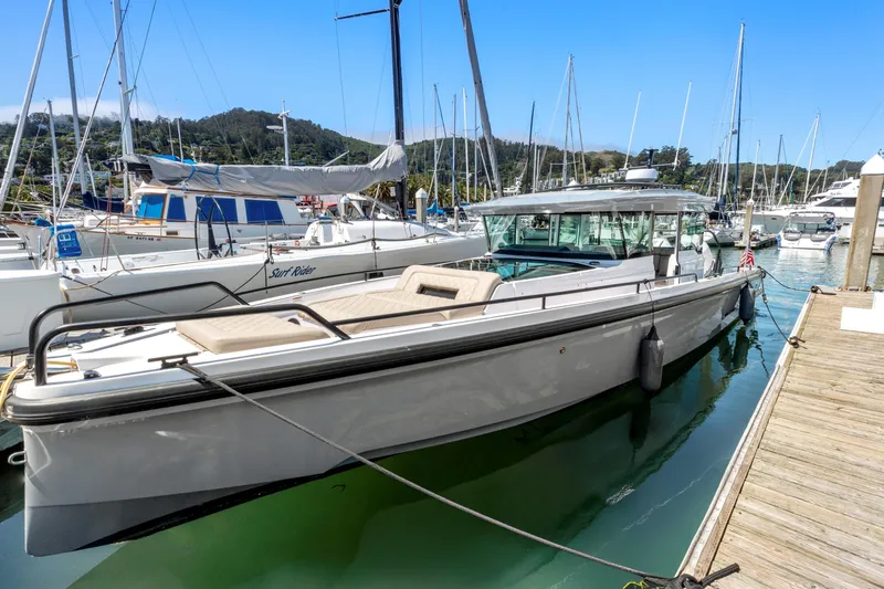 The Image of 2022 Axopar 37 Cross Cabin Brabus Trim docked in a marina, surrounded by sailboats. - 0