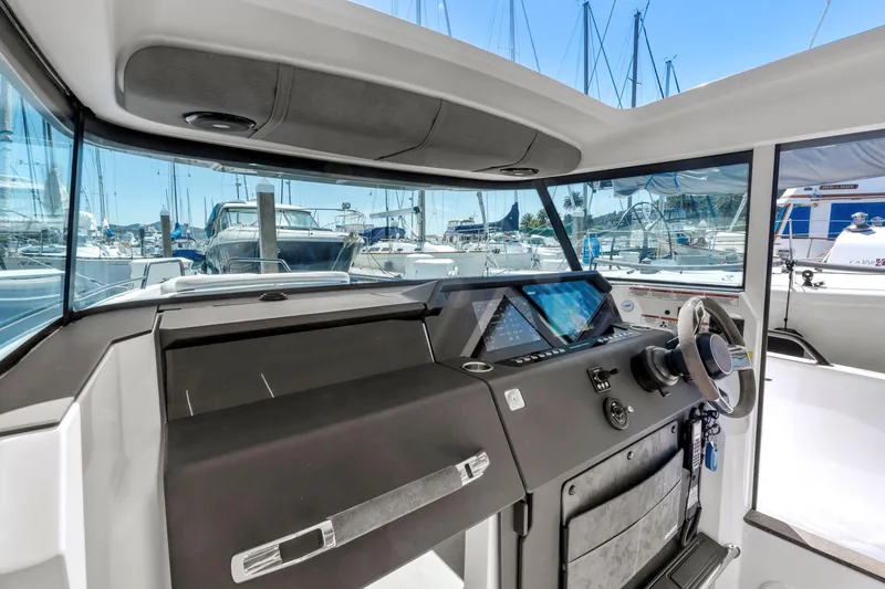 Slide: The Image of 2022 Axopar 37 Cross Cabin Brabus Trim interior with modern dashboard and marina view. - 10