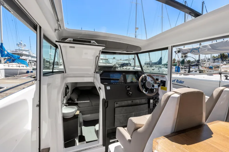 Slide: The Image of 2022 Axopar 37 Cross Cabin Brabus Trim interior with helm, seating, and marina view. - 14