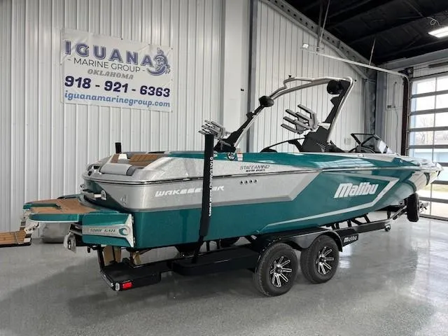 Slide: The Image of 2025 Malibu Wakesetter 24 MXZ boat in showroom, teal and silver design, on trailer. - 3