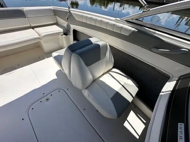 Slide: The Image of 2013 Bayliner 190 Bowrider interior with white and gray seating, docked by water. - 10