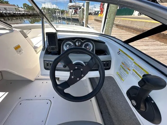 Slide: The Image of 2013 Bayliner 190 Bowrider dashboard with steering wheel and controls at marina. - 13
