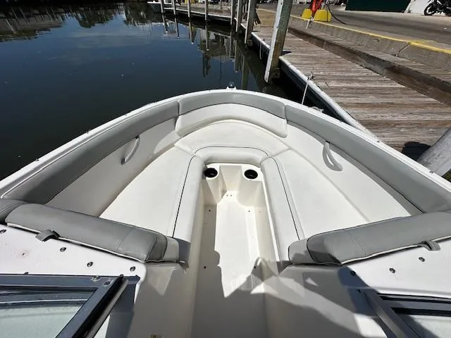 Slide: The Image of 2013 Bayliner 190 Bowrider boat interior with seating, docked by calm water. - 14