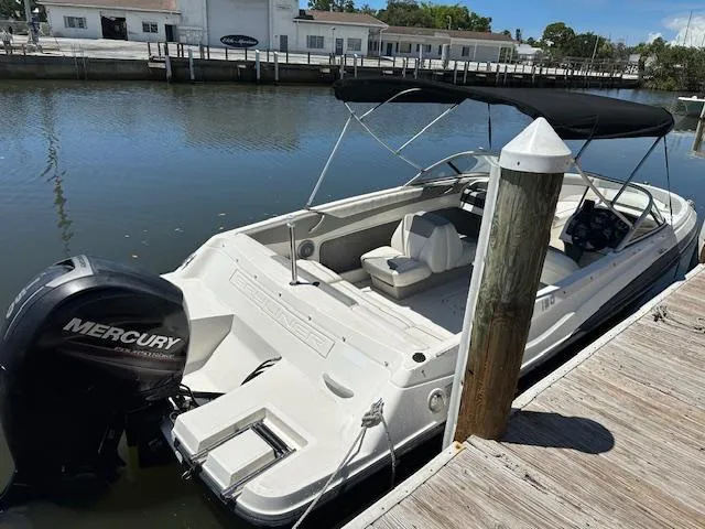Slide: The Image of 2013 Bayliner 190 Bowrider with Mercury outboard engine docked by the water. - 2