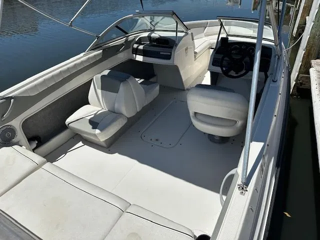 Slide: The Image of 2013 Bayliner 190 Bowrider interior with seating and steering wheel, docked by the water. - 6