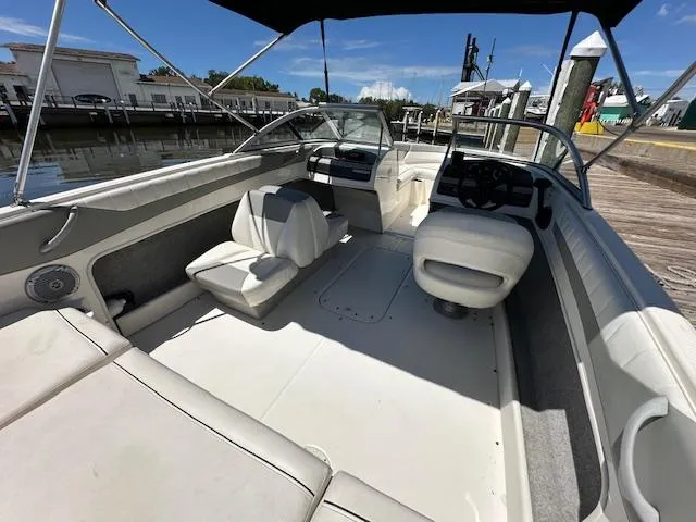 Slide: The Image of 2013 Bayliner 190 Bowrider interior with seating and steering wheel, docked by the water. - 7