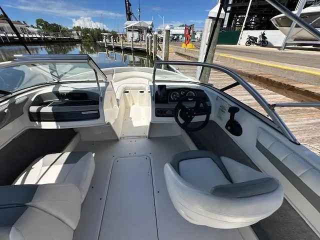 Slide: The Image of 2013 Bayliner 190 Bowrider interior with seating and steering wheel, dockside view. - 9
