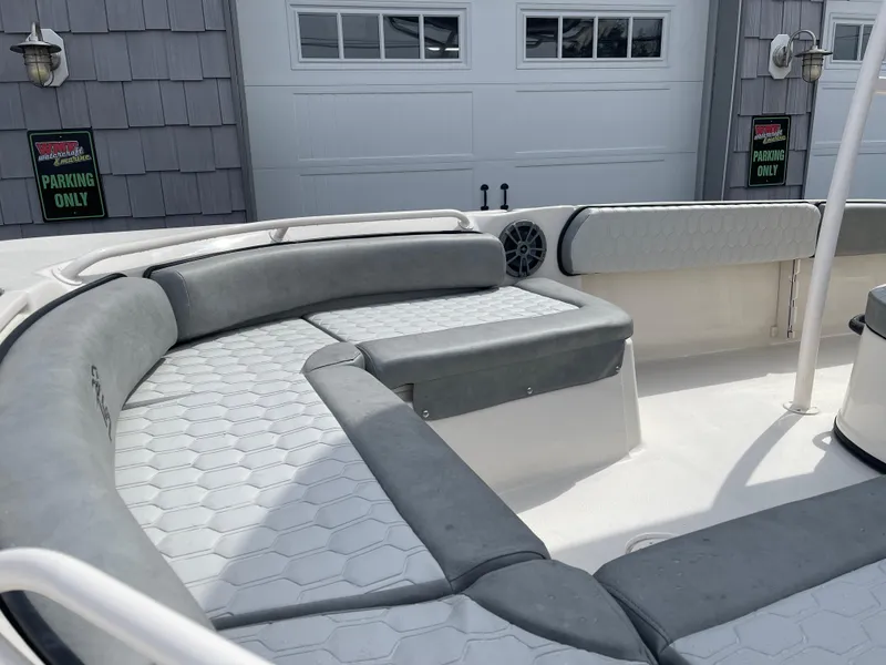 Slide: The Image of 2025 Carolina Skiff 21 Ultra Elite boat with gray seating, parked near a garage. - 17