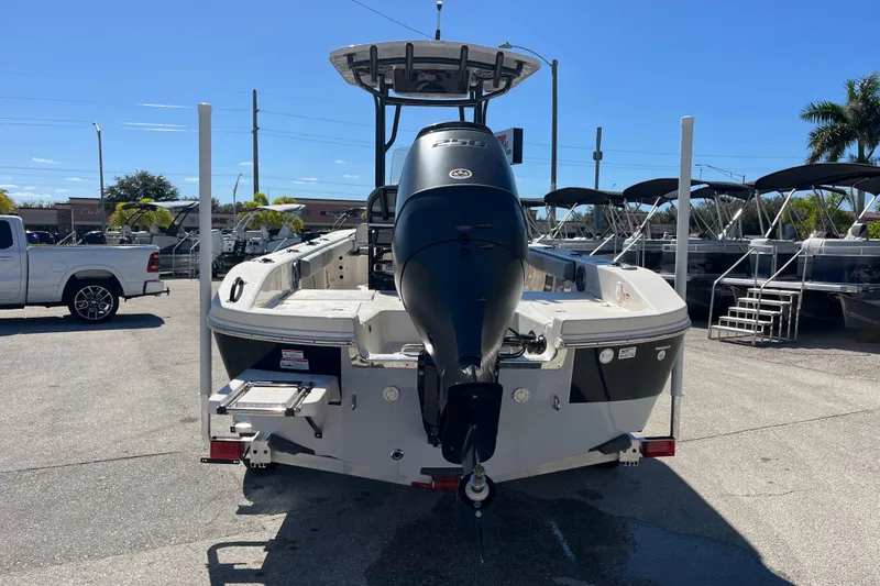 Slide: The Image of 2025 Carolina Skiff 24 Ultra Elite boat with outboard motor, parked outdoors. - 11