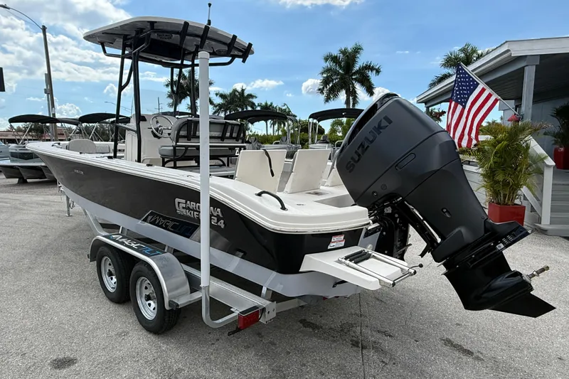 Slide: The Image of 2025 Carolina Skiff 24 Ultra Elite boat with Suzuki engine on trailer, American flag nearby. - 6