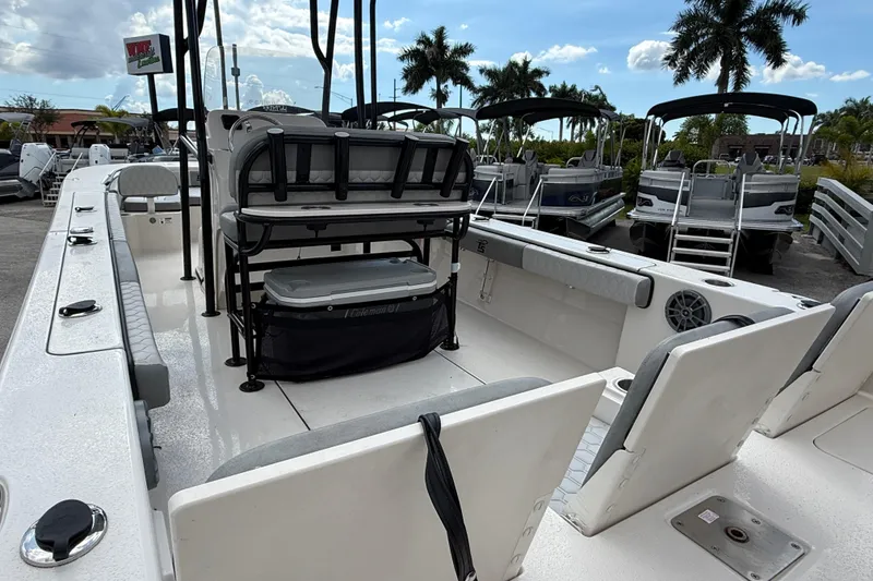 Slide: The Image of 2025 Carolina Skiff 24 Ultra Elite boat interior with seating and storage, parked outdoors. - 7