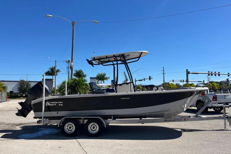 Slide: The Image of 2025 Carolina Skiff 24 Ultra Elite boat on trailer, parked outdoors under clear blue sky. - 9