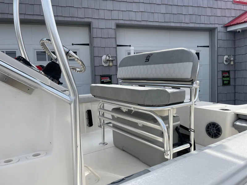 Slide: The Image of 2025 Carolina Skiff 19 LS boat interior with steering console and seating, parked outdoors. - 10