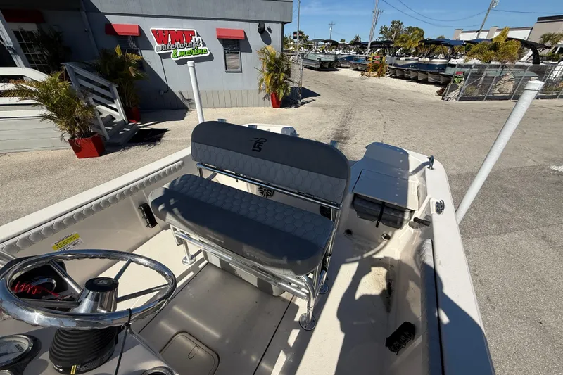 Slide: The Image of 2025 Carolina Skiff 19 LS boat interior with seating and steering wheel at a marina. - 25