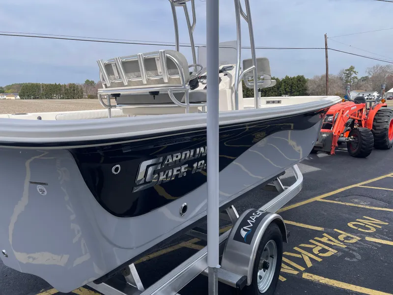 Slide: The Image of 2025 Carolina Skiff 19 LS boat on trailer, parked outdoors under clear blue sky. - 5