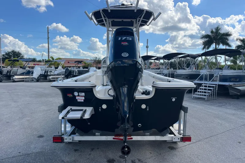 Slide: The Image of 2025 Carolina Skiff 21 LS boat with outboard motor, parked outdoors under a cloudy sky. - 27