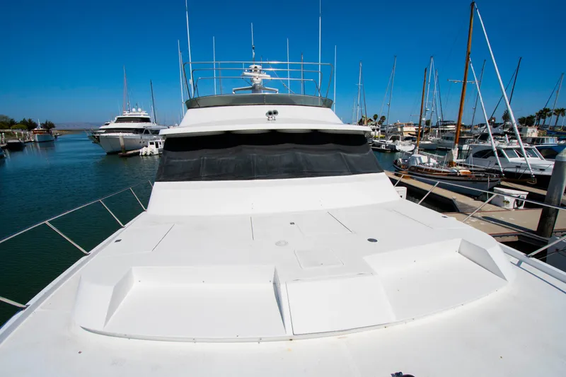Slide: The Image of 1988 Knight & Carver Motoryacht docked in a marina, surrounded by sailboats under a clear blue sky. - 53