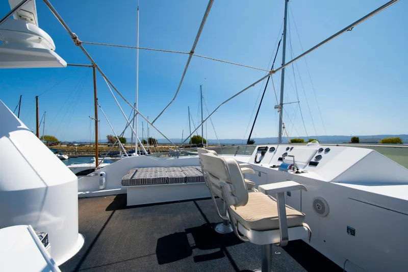 Slide: The Image of 1988 Knight & Carver Motoryacht deck with control panel and seating, under clear blue sky. - 8