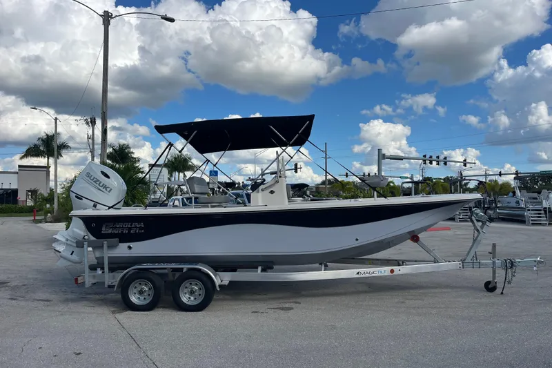 Slide: The Image of 2025 Carolina Skiff 21 LS boat on trailer, parked outdoors under a cloudy sky. - 2