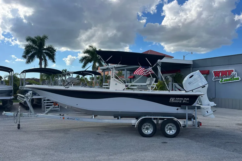 Slide: The Image of 2025 Carolina Skiff 21 LS boat on trailer, parked outdoors under cloudy sky. - 6