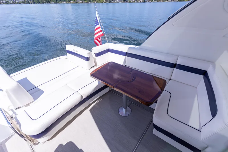 Slide: The Image of 2011 Sea Ray 450 Sundancer yacht deck with seating and table, American flag, on calm water. - 13