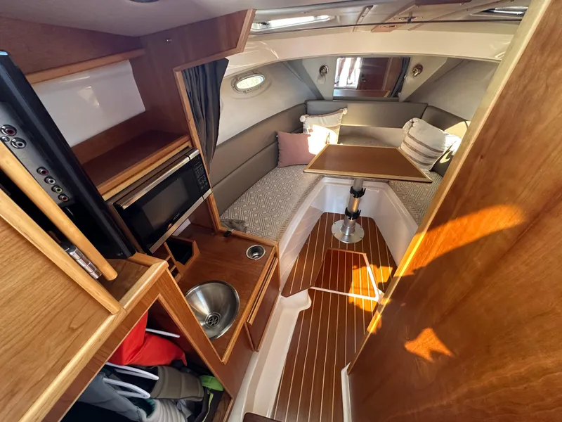 Slide: The Image of 2019 Cutwater C-28 cabin interior with kitchenette, seating area, and wooden finishes. - 20