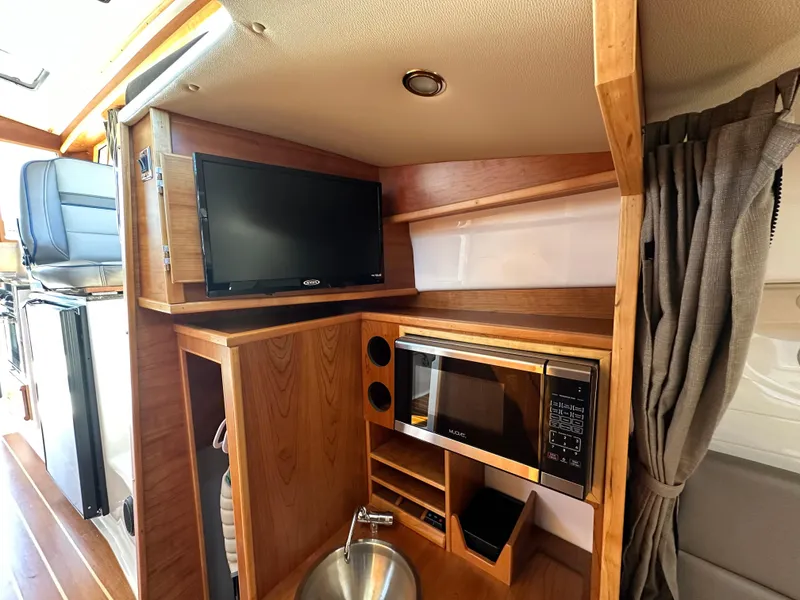Slide: The Image of 2019 Cutwater C-28 interior with TV, microwave, and wooden cabinetry. - 24