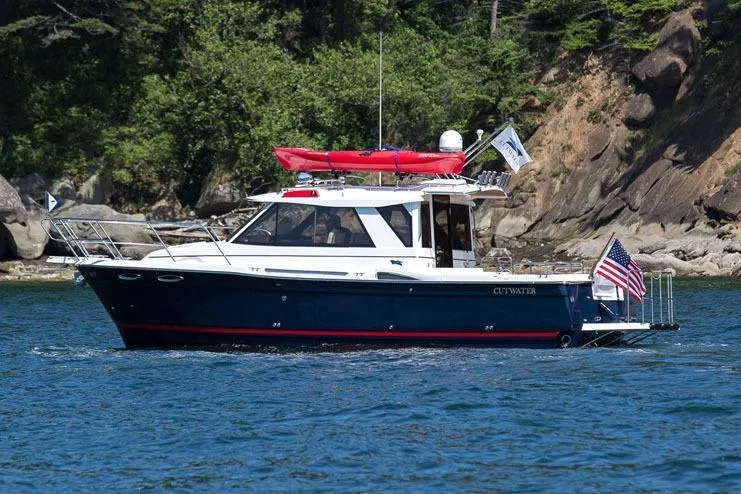 Slide: The Image of 2019 Cutwater C-28 boat cruising on a scenic lake with lush greenery. - 39