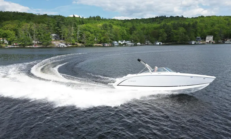 Slide: The Image of 2021 Cobalt R5 boat cruising on a scenic lake with lush green forest backdrop. - 23