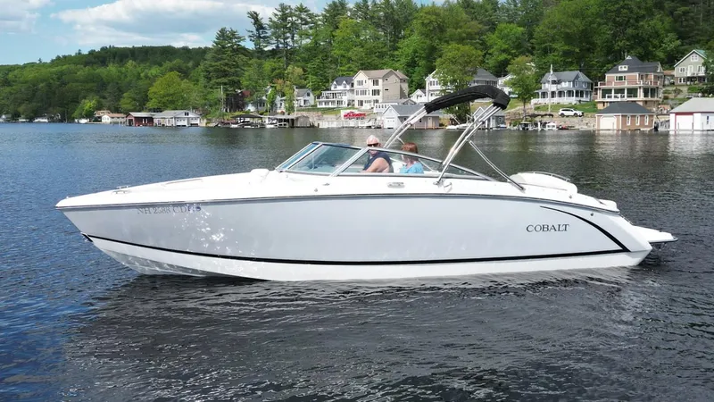 Slide: The Image of 2021 Cobalt R5 boat cruising on a scenic lake with houses and trees in the background. - 25