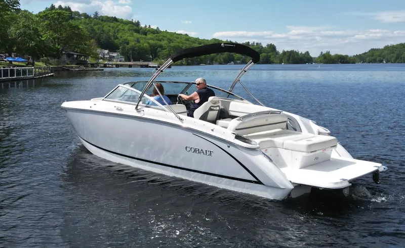 Slide: The Image of 2021 Cobalt R5 boat cruising on a scenic lake with lush green surroundings. - 27