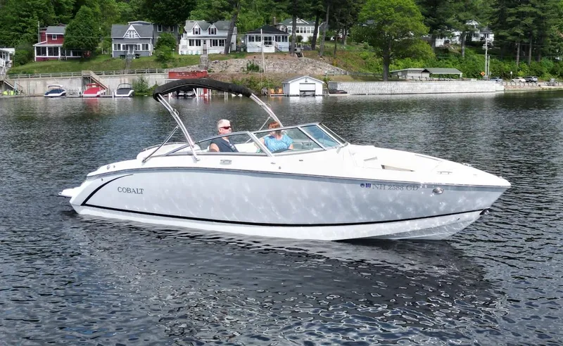 Slide: The Image of 2021 Cobalt R5 boat cruising on a serene lake with houses in the background. - 28
