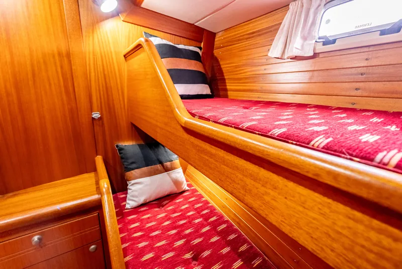 Slide: The Image of Bunk beds in 1997 Farr 60 Pilot House with red patterned bedding and wooden interior. - 40