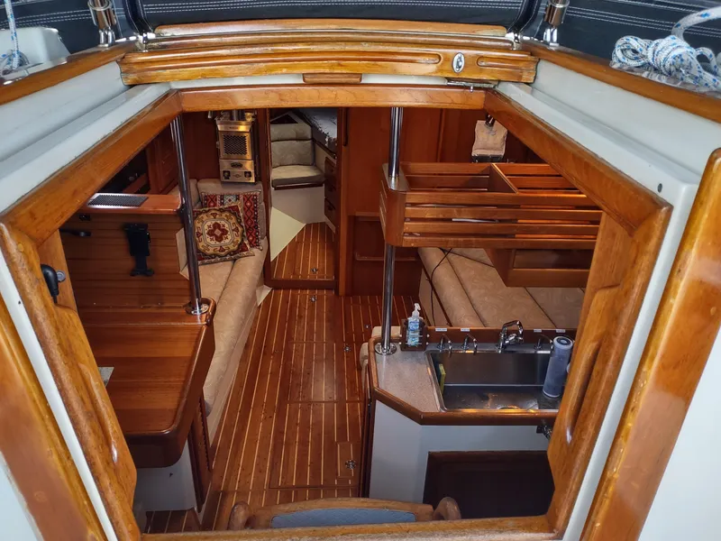 Slide: The Image of Interior view of a 1997 Pacific Seacraft 37 sailboat, featuring wood finishes and cozy seating. - 22