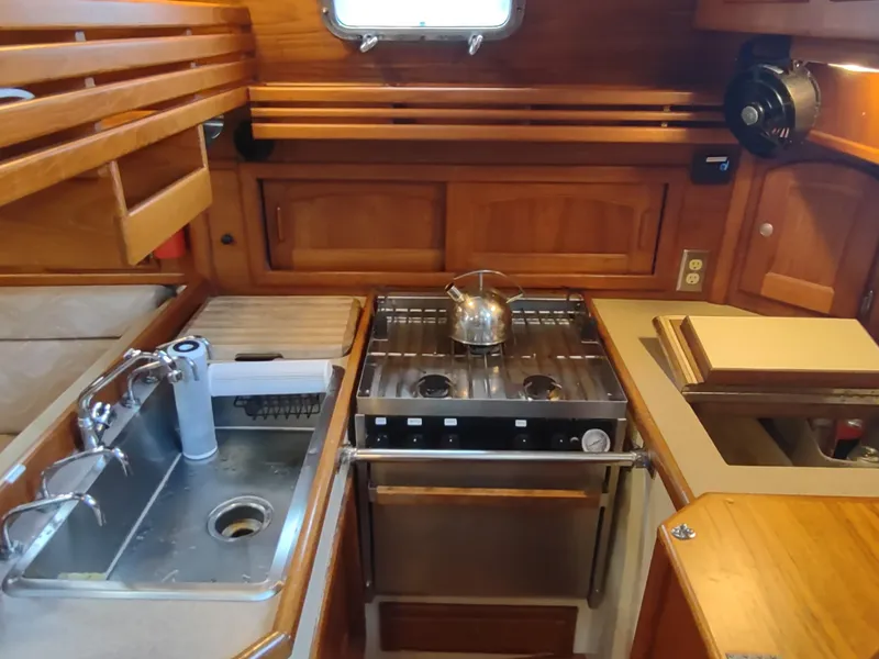 Slide: The Image of Galley of 1997 Pacific Seacraft 37 sailboat with stove, sink, and wooden cabinetry. - 29
