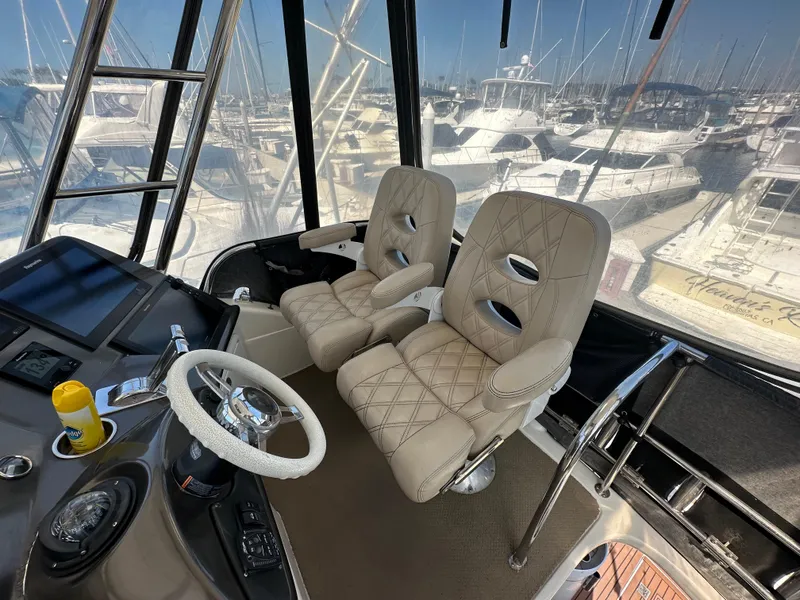 Slide: The Image of 2003 Riviera 37 Flybridge helm with dual beige seats and marina view. - 2