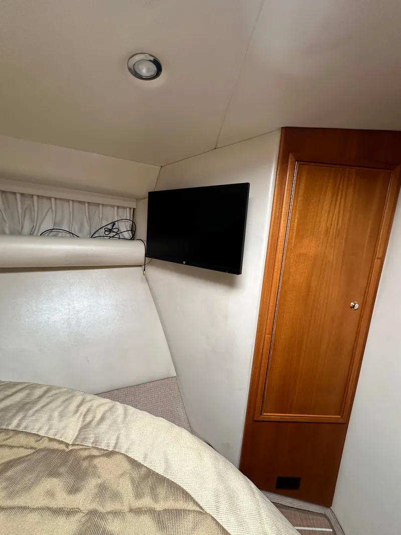 Slide: The Image of 2003 Riviera 37 Flybridge cabin interior with TV and wooden cabinet. - 22