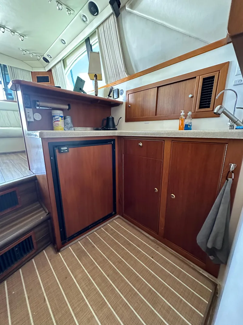 Slide: The Image of 2003 Riviera 37 Flybridge yacht interior with wooden cabinetry and compact kitchen area. - 25