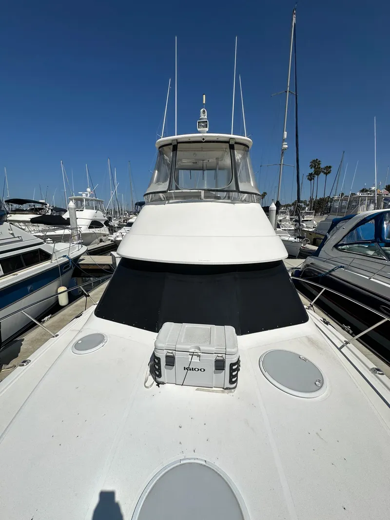 Slide: The Image of 2003 Riviera 37 Flybridge yacht docked at marina under clear blue sky. - 29