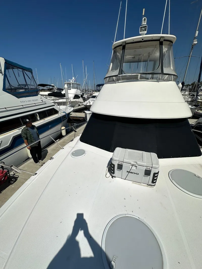 Slide: The Image of 2003 Riviera 37 Flybridge yacht docked at marina under clear blue sky. - 30