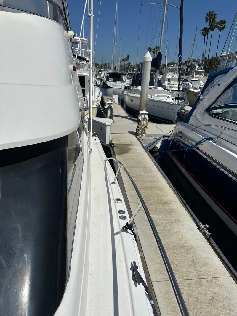 Slide: The Image of 2003 Riviera 37 Flybridge yacht docked at marina with clear blue sky. - 32