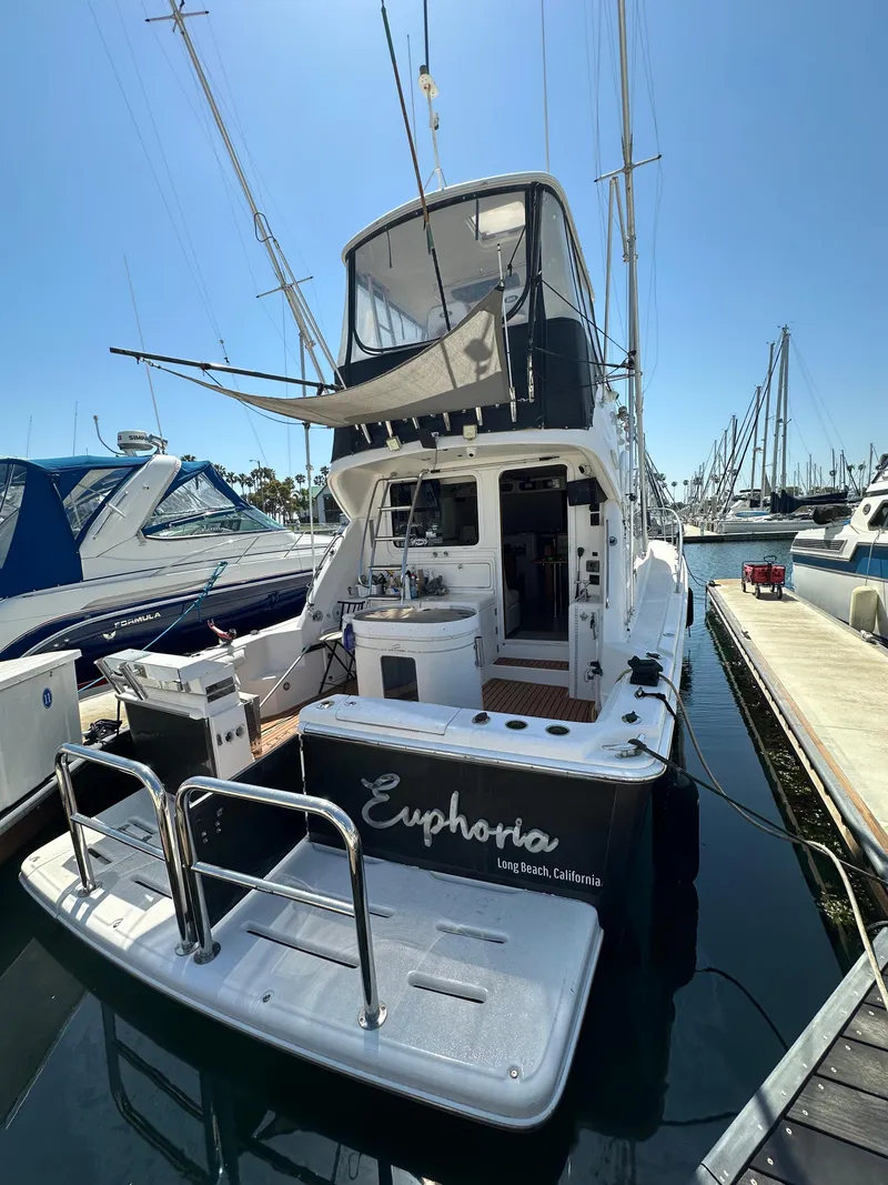 Slide: The Image of 2003 Riviera 37 Flybridge yacht named "Euphoria" docked at a marina. - 34